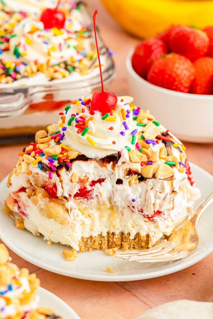  Individual serving-sized banana split parfaits in clear glasses, layered with crust, cream, fruit, and toppings.