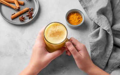 Healthy homemade detox drink preparation using lemon juice, ginger root, raw honey, and water.