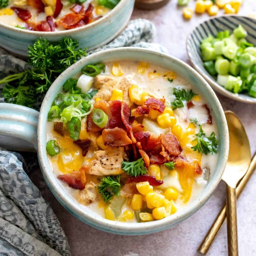 Creamy chicken corn chowder served in a white bowl with herbs and pepper